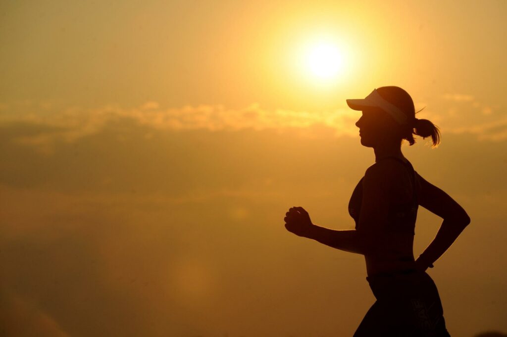 exercises for osteoporosis, young woman running in front of a sunset.