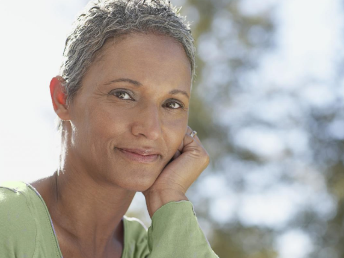 root cause of hair loss, Up-close photo of a person with light brown skin and silver/gray crop hair who appears to be in their 40s or 50s. They are looking at the camera with a light smile on their face, representing the possibility for hair regrowth at various ages through addressing the root cause of hair loss.
